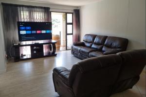 a living room with a leather couch and a flat screen tv at Triton Heights 7 in Linkside