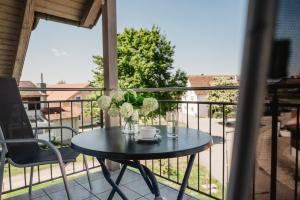 a table with a vase of flowers on a balcony at Appartementhaus am Brückerl in Bad Füssing