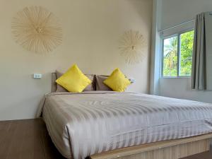 een slaapkamer met een groot bed met gele kussens bij Oh Town Villa in Thongsala