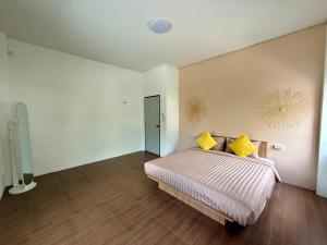 een slaapkamer met een bed met gele kussens erop bij Oh Town Villa in Thongsala +1 foto