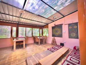 a living room with a table and chairs and windows at Royal Star Kasol in Kasol