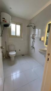 a white bathroom with a toilet and a sink at Comfy Tourist Corner - Giza - Hotel Apartments in Cairo +236 photos