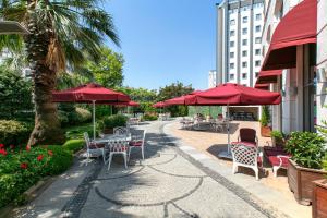 a patio with tables and chairs with red umbrellas at Limak Eurasia Luxury Hotel in Istanbul