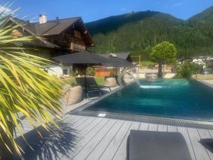 a swimming pool with a house and mountains in the background at Hoagascht in Flachau