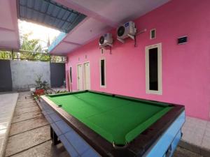 a pink room with a pool table in it at Hotel O Asipra House in Banyuwangi