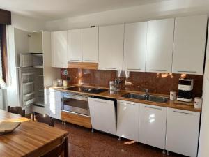 a kitchen with white cabinets and a wooden table at Poma Luxury 1 Piano in Borno