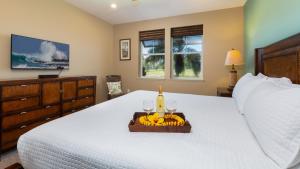 a bedroom with a bed with a bottle of wine and bananas at BY THE SEA VILLA Cheerful 3BR Halii Kai Home with Golf and Ocean Views in Waikoloa