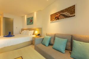 a hotel room with a bed and a couch at C114 Romantic Getaway Seaview, Pool, Gym Access in Ban Saiyuan (1) +20 photos