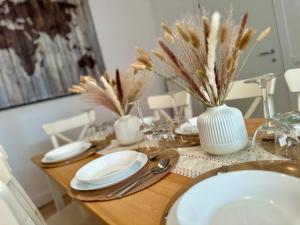 a wooden table with plates and a vase on it at Domoi Property Apartment in Pisa