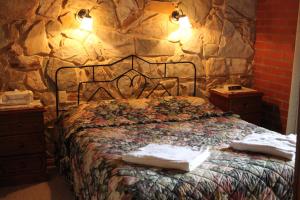 a bedroom with a bed with a stone wall at Langmeil Cottages in Tanunda