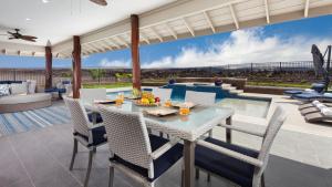 a patio with a table and chairs and a pool at ALOHA SPIRIT AinaMalu 4BR Home with Outdoor Living Room and Pool in Waikoloa