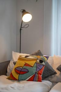 a colorful pillow sitting on a bed with a lamp at Special TRIO PICASSO Apartment Basel, Bahnhof Grossbasel 10-STAR in Basel +60 photos