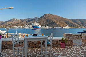 a table and chairs on a patio with a boat in the water at Nicolas House 3 in Rakhídhion