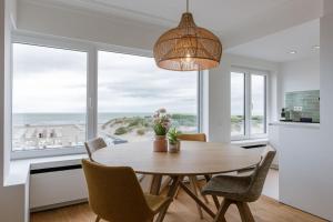 a dining room with a table and chairs with a view of the ocean at Huswell - Bright & Stylish Apartment Near Beach with Sea view in Knokke-Heist