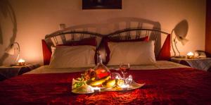 カト・ルートラキにあるDrosia Hotelのベッドの上にフルーツとワイン1杯のトレイを用意しています。