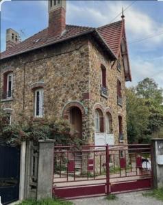 ein altes Steinhaus mit einem Zaun davor in der Unterkunft Villa Petit Prince - Logement entier in La Celle-sous-Gouzon