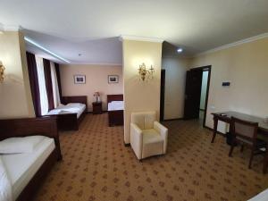a hotel room with two beds and a chair at Hotel YOSHLIK in Navoi +4 photos