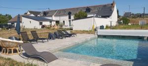 a swimming pool with chairs next to a house at Domaine du Saugé in La Riche