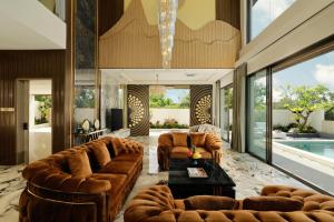 a living room with leather furniture and a swimming pool at Villa Kalem Uluwatu by Nakula in Uluwatu