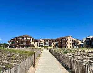 a walkway leading to a row of apartment buildings at Evasion cosy aux pieds de l'Océan in Lacanau
