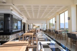 a restaurant with tables and chairs and windows at Grand Blue Beach Hotel in Kardamaina