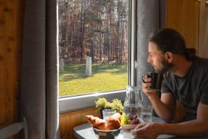 a man sitting at a table with a bowl of food and a window at Maringotka Slaměnka u menhirového kruhu - U Slaměnky in Hněvětice