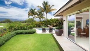 ein Hinterhof mit einem grünen Rasen und einem Haus in der Unterkunft ENDLESS SUMMER Elegant KaMilo Home with Heated Pool and Guest Cottage in Waikoloa