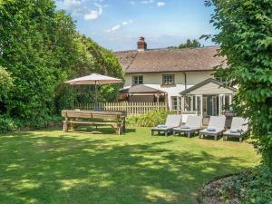 a backyard with a picnic table and chairs and an umbrella at 2 Pigsfoot Cottages in Tiverton
