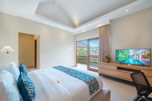 a bedroom with a large bed and a flat screen tv at Villa Ellyne Canggu by Nagisa Bali in Canggu