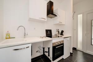 une cuisine blanche avec un évier et une cuisinière dans l'établissement Studio Calme avec terrasse, à Nancy