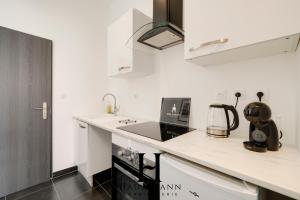 une cuisine blanche avec un évier et un micro-ondes dans l'établissement Studio Calme avec terrasse, à Nancy