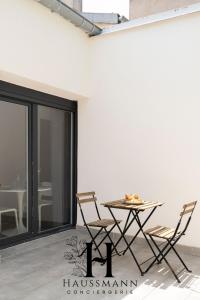 d'une terrasse avec une table et des chaises sur un mur blanc. dans l'établissement Studio Calme avec terrasse, à Nancy