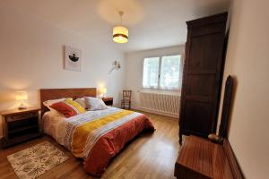 a bedroom with a bed and a wooden floor at Gîte Coralizacias in Plérin