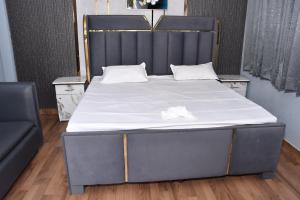 a bed with a black headboard and white sheets at The Farmstay in Jāmb