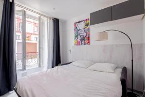 Un dormitorio con una cama blanca y una ventana. en Charmant Studio à Saint-Mandé, en Saint-Mandé