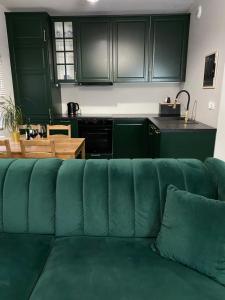 a green couch in a kitchen with green cabinets at Dwupoziomowe Komfortowe Mieszkanie Krzyki z Dwiema Łazienkami in Wrocław