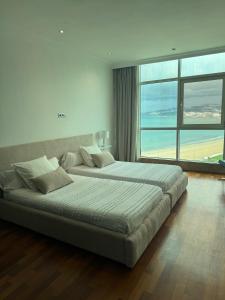 ein großes Bett in einem Zimmer mit einem großen Fenster in der Unterkunft Exquisite Top Floor Apartment in the Bay of Tanger in Tangier