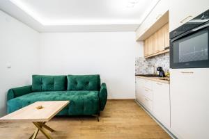 a living room with a green couch and a table at Panorama V Lux Vrnjačka Banja in Vrnjačka Banja