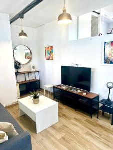a living room with a couch and a tv at Loft A Mariña Lucense in San Ciprián
