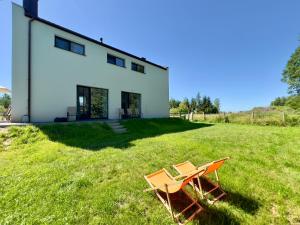 a house with two chairs and a table in the grass at Mazury Lake House Sailing & Nature in Dobrzyki
