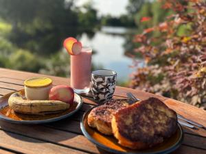 a wooden table with a plate of breakfast food and a drink at Les Rives De Bel Air - Hébergements - Camping - Caravaning in Saint-Siméon