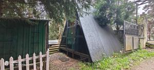 a fence next to a green shed and a gate at Nest 'N' Woods in Ooty