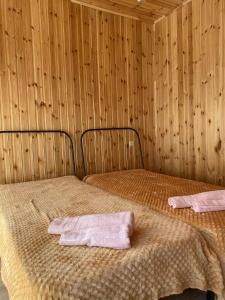 a bedroom with two beds in a wooden wall at Green house Cottage in Itʼkhvisi