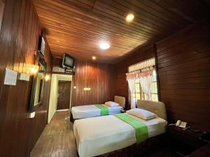 zwei Betten in einem Zimmer mit Holzwänden in der Unterkunft Green Valley Resort Bandungan in Bandungan
