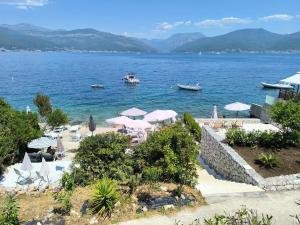 a beach with chairs and umbrellas and boats in the water at Apartment Krasici in Krašići