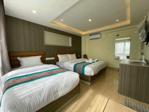una camera d'albergo con due letti e una televisione di President Hotel Airport a Kathmandu