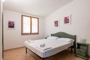 a bedroom with a bed with white sheets and a window at Villa Azzurra con piscina in Tertenìa +30 photos