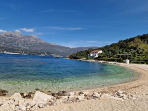 a beach with blue water and mountains in the background at Agape Rose Hotel in Tivat