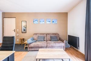 a living room with a couch and a tv at Appartement spa fleures d'Orelle in Orelle