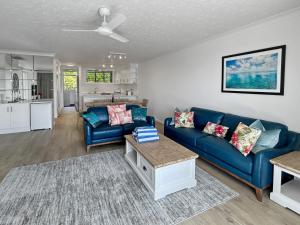 a living room with a blue couch and a table at Beach Lodges Premium in Hamilton Island +17 photos